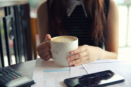 一名商业妇女手拿咖啡和商业纸图片