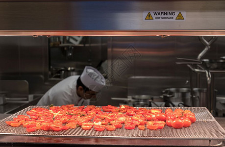 烹饪厨师在餐馆商业不锈钢厨房做烤西红柿在现代商业厨房做烤西红柿图片