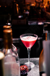 玛蒂尼酒杯中美丽的红色激情果子鸡尾酒吧柜台有深色背景图片
