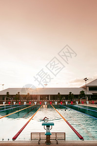 2013年4月7日泰国标准游泳池跳台跃和游泳者在日落时享受游泳图片