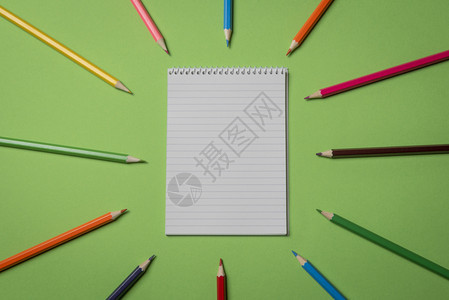 绿色彩桌上的木铅笔和空白螺旋记本直接在有复制空间的视图上方图片