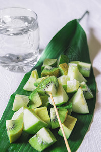 绿色水果混合沙拉在大叶子和一杯水上在白桌脱毒食品素甜点健康饮环境图片