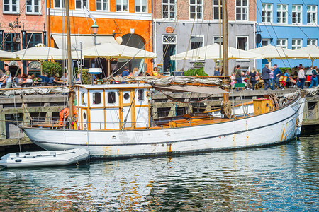 由Nyhavn车道停靠的旧帆船有行走的游客和餐馆斗蓬登记图片