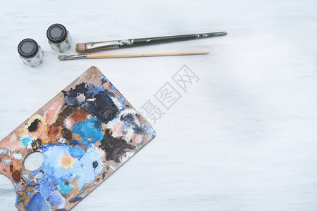 艺术家配有彩色油画笔和白木背景的油漆笔调色板艺术概念背景图片