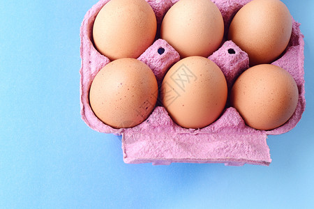 6个褐蛋在盒子上的顶部视图新鲜食物概念浅蓝色背景图片