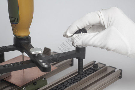 工人双手在雕刻设备受电弓与数控雕刻机凸版字母在白色背景上工人手上的雕刻装置受电弓与数控刻版机的凸版字母图片