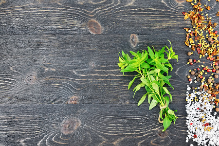 一堆新鲜的绿色香草盐辣椒芬纳格利克种子与黑木板相对图片