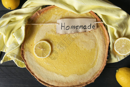 黑桌子上的柠檬馅饼和黄色的厨房毛巾上面贴着在标签上的文字面是烤甜食柑橘点图片