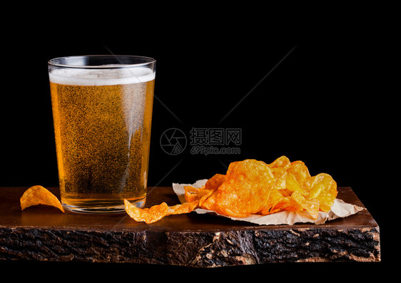 玻璃啤酒和土豆脆饼在旧木板上吃点心黑底的木板上图片