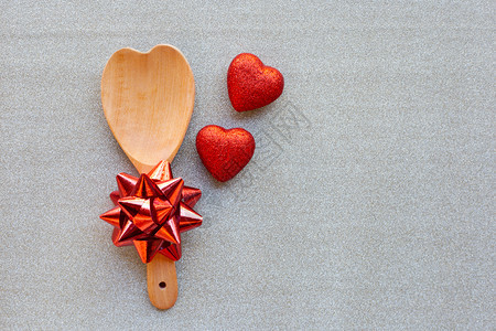 红心形和木勺红弓在银色闪光纸背景在爱的概念情人节图片