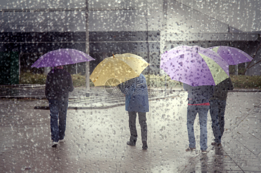 4个人在多彩的雨伞和通过窗口看到满是雨滴的图片