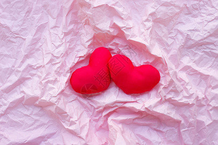 valenti在粉红色折叠纸面背景上的红心顶部视图图片