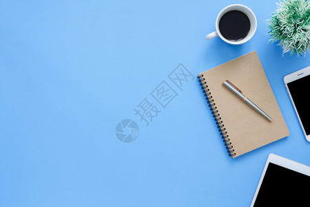 办公桌工作空间平面板电话咖啡杯和蓝面纸背景笔记本工作空间的顶层图像模拟照片图片