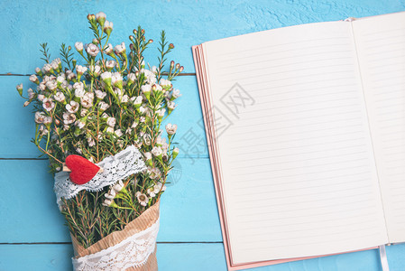 白色小花装在旧纸和丝带上靠近空议程放在蓝色的桌子上面视图母亲日框架春季背景图片