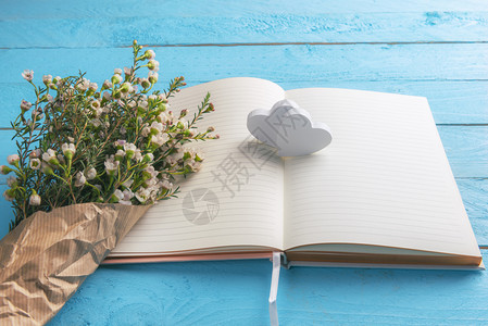 白百何杂志写真两颗木心放在空笔记本页上白花束放在旧纸上蓝木桌背景