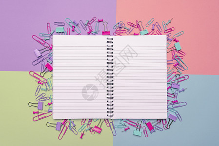 空白开放笔记本和大量办公用品纸夹剪片和多彩背景的推针图片
