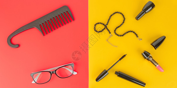 女优雅的附属品眼镜化妆首饰和梳子放在黄色和红背景上图片