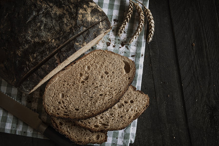 土制面包在生锈的桌子上平的面图象和厨房毛巾上的切片面包图片