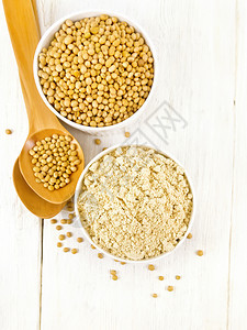 两个白碗中的大豆面粉和上的木板背景勺子图片