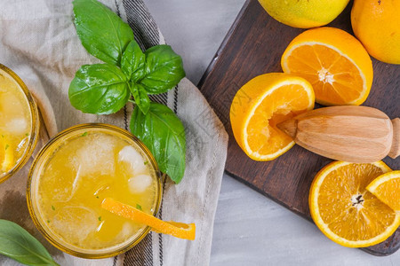 木制橙汁上面装有冰立方体和巴西尔玻璃叶子图片