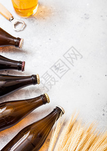 玻璃瓶的手工艺啤酒生小麦和开瓶器放在石餐桌背景上图片