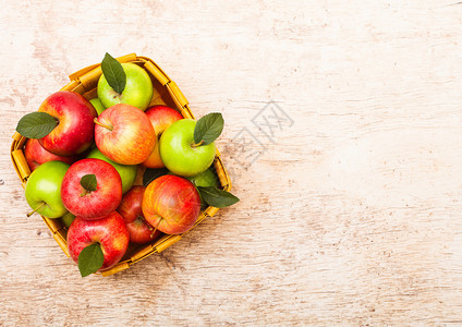 红苹果和绿用木本底的旧篮子图片
