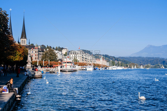 2013年9月4日卢塞伦瑞士湖润滑油海岸游客观光船和码头背景的霍夫基切圣李德加教堂钟塔图片