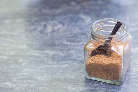 咖啡店灰色石桌上的装着玻璃瓶中的木勺棕色糖图片