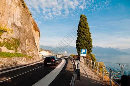 路边的汽车Swishzerland开在湖面的汽车韦镇附近的chexbrs村和Switzerland的Motreux路边有岩石悬崖背景