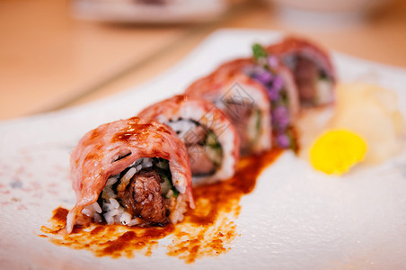 瓷砖板上鲜美的日本黄瓜牛肉寿司卷和酱汁近镜头图片
