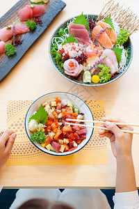 在木桌顶端拍摄到的镜头中各种新鲜的日本菜生鱼片寿司和卡森顿溢价的日本菜生鱼米饭碗图片