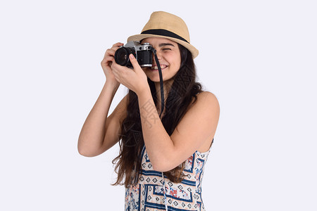 穿着夏帽的年轻女子肖像站在古董相机上旅行概念孤立的白色背景图片