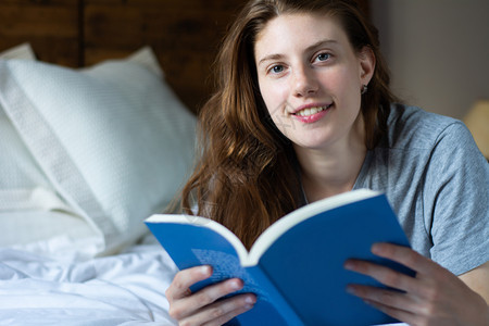 年轻女孩在床上读书图片