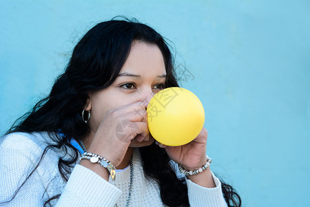 年轻拉丁女人的肖像正在吹气球图片