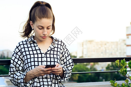 美丽的年轻红发女在屋顶上用智能手机发信息图片