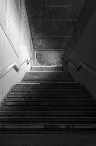地下通道的楼梯有混凝土墙壁和低光金属护栏图片