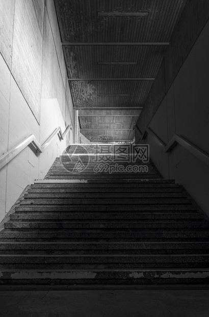 地下通道的楼梯有混凝土墙壁和低光金属护栏图片