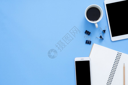 办公桌工作空间平面板电话咖啡杯和蓝面纸背景笔记本工作空间的顶层图像模拟照片图片