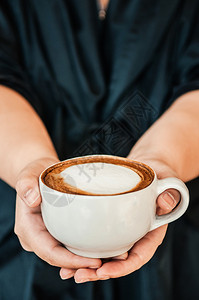 女手举着一杯咖啡热卡布奇诺上面有漂亮的牛奶近镜头图片