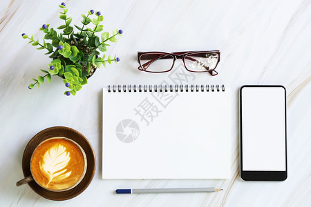 现代白色大理石桌上的平板办公用具笔记本的空白页用屏幕移动咖啡杯眼镜铅笔和绿色植物锅图片