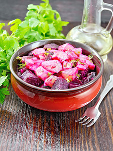 甜菜和土豆沙拉用植物油和醋在碗里调味欧芹叉子放在木板上图片