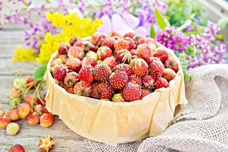 野生成熟的草莓在木板背景上装有羊皮卷毛和野花的树皮箱中图片