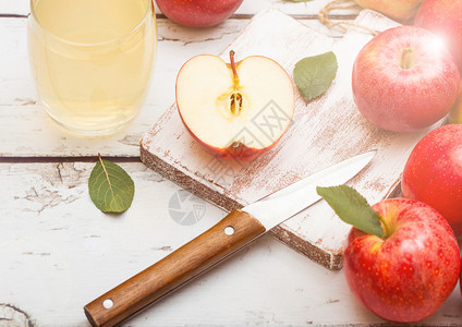 玻璃杯新鲜有机苹果汁红在砍刀板上木制背景图片