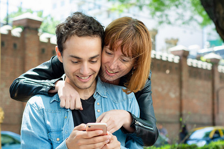 年轻夫妇在户外智能手机上使用应程序玩得开心图片