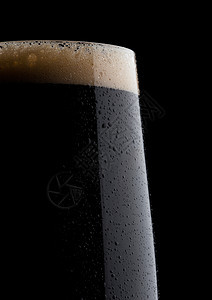 黑色底宏中带有泡沫和露珠的深啤酒图片