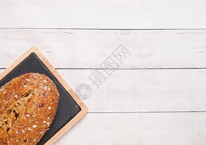 木板背面有燕麦和厨房毛巾的新鲜烤面包图片