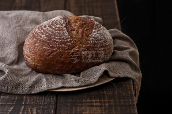 黑木板上配有厨房毛巾的新鲜烤面包图片
