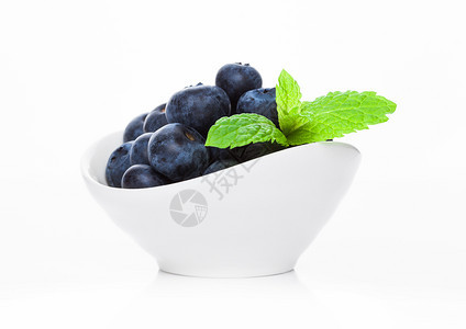 白碗中的新鲜健康有机蓝莓白底薄荷叶图片
