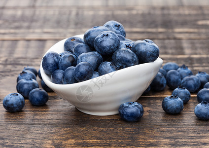 以木制背景在白碗中的新鲜健康有机蓝莓图片