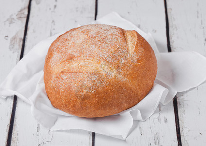 配有厨房毛巾和白木板上小麦的新鲜烤面包图片